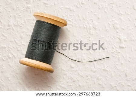 Wooden bobbin of black thread in closeup