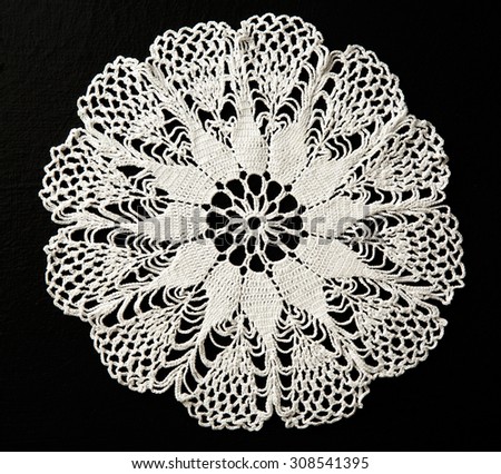 Crocheted white lace decorative napkin on black