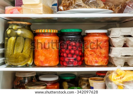 Pickled vegetables in jars on shelf in refrigerator