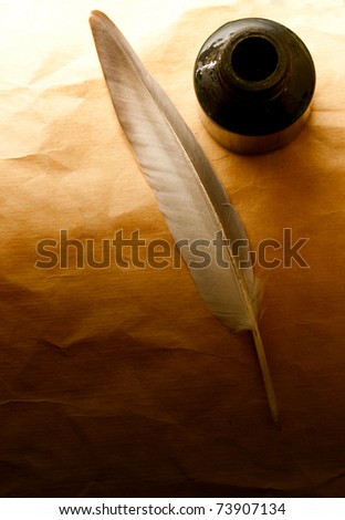 Feather and ink bottle isolated on paper background