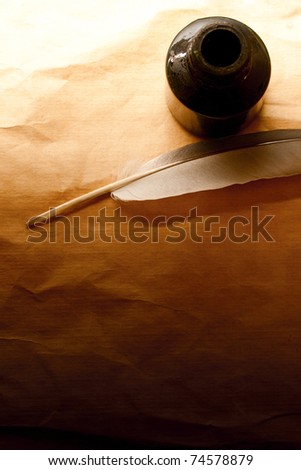Feather and ink bottle isolated on paper background