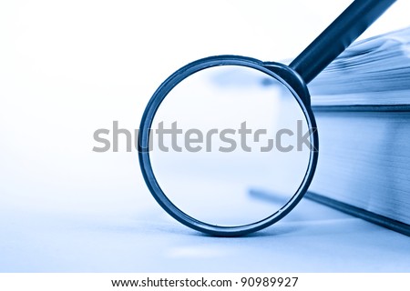 A pile of paper and a book through the magnifying glass