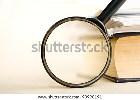 A pile of paper and a book through the magnifying glass