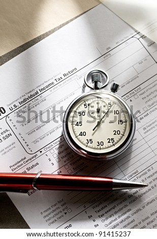 Tax form, red pen and stopwatch