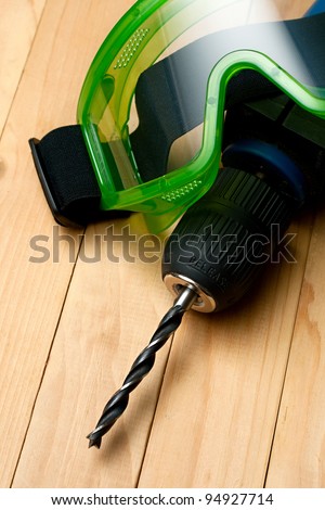 Hand drill and goggles on wooden background