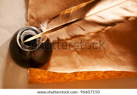 Feather and ink bottle on paper background
