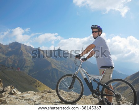 young man with a full suspension bike in mountains environment