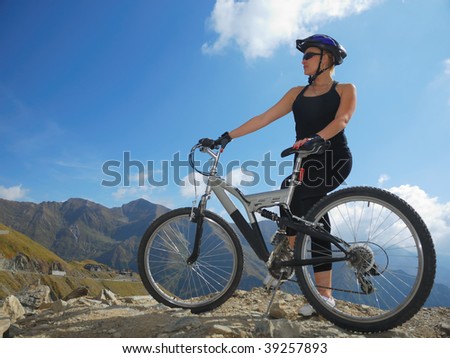 young female with full suspension bike looking at mountain landscape