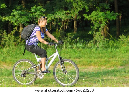 happy blonde young woman traveling on country side with bike