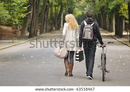 back side view of two teenagers walking in park and a bile