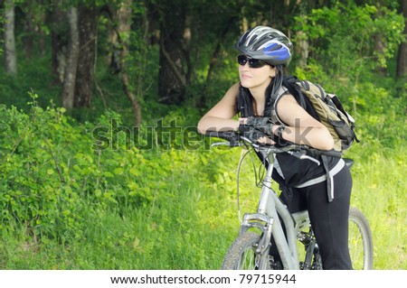 young biker woman getting rest in forest area and looking at copy space