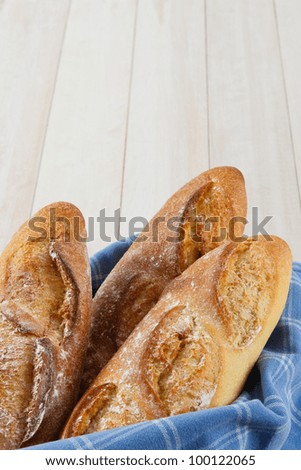 Fresh baked crusty loaves of French Baguette bread wrapped in a blue towel with copy space