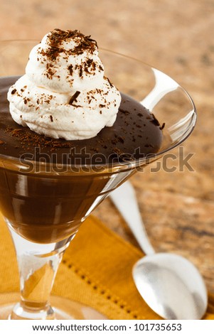 Chocolate pudding in an elegant glass is topped with whipped cream and chocolate shavings