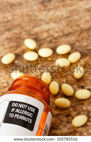 Prescription bottle with peanut allergy warning label shows yellow capsules spilled on a brown background - overhead view with copy space.
