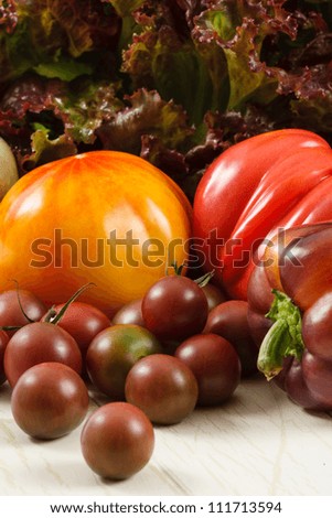 Colorful fresh heirloom tomatoes with purple pepper and red leaf lettuce