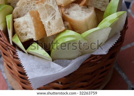 Sliced apples and bread in basket on tiled table