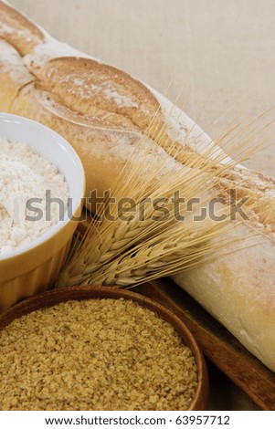 Crusty golden baguette bread with flour, wheat and wheat germ illustrate tasty food or wheat allergens with copy space.