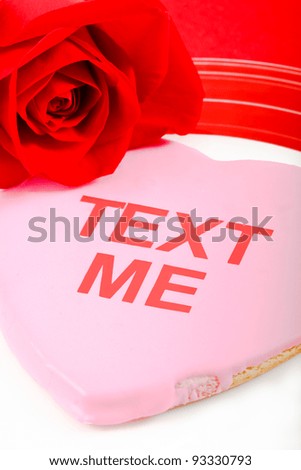 A pink cookie and red rose use the tech-oriented phrase Text Me to send a flirtatious message to a loved one.