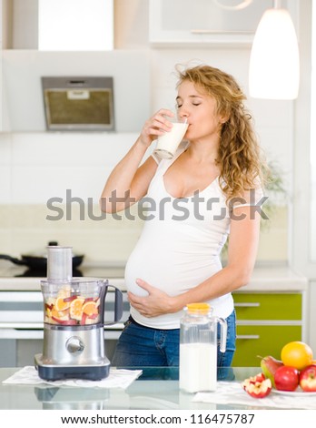 pregnant woman drinking milk at kitchen