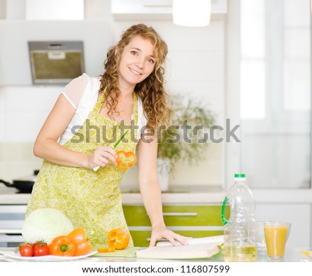 pregnant mother making healthy food standing happy smiling in kitchen. looking at camera.