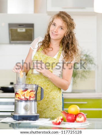 Portrait of a smiling pregnant woman cooking in her kitchen. looking at camera.