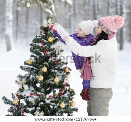 mother and the daughter decorate a Christmas tree