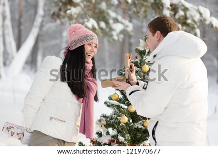 lovers give gifts in the wood near the decorated tree