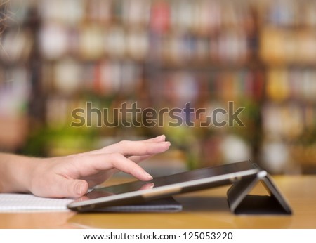 Hands typing on tablet computer in library