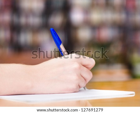the hand of the girl writes to writing-book in library