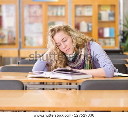 female student reads the book in library