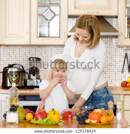 mother with the daughter make a dinner in kitchen