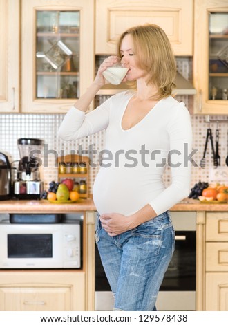 pregnant woman drink milk in kitchen