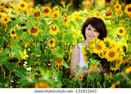 Young  woman with a bouquet of sunflowers in the field