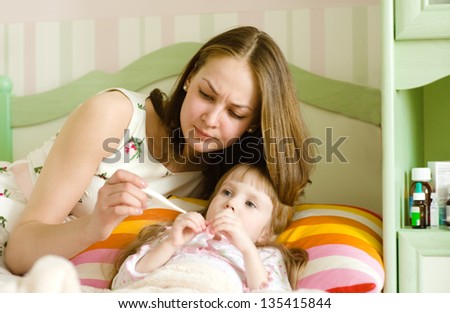 Sick kid with high fever laying in bed and mother taking temperature