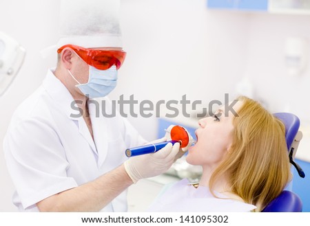 young woman with open mouth receiving dental filling drying procedure.