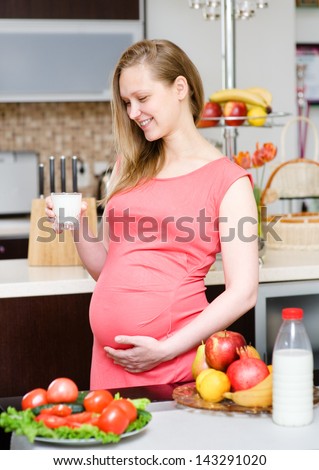 Pregnant mother drinks the milk on the house kitchen