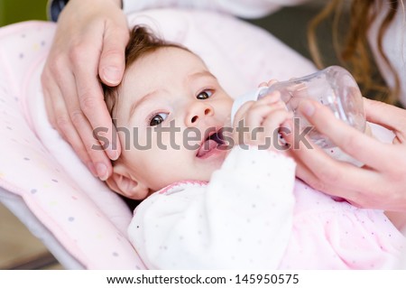 Mother feeding newborn daughter with feeding bottle