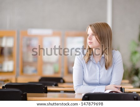pretty young college student in a library. looking away