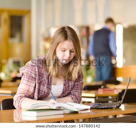 female student with laptop working in library