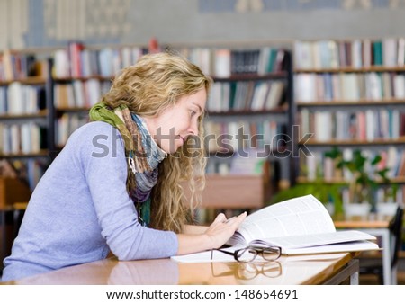 female student reads the book in library