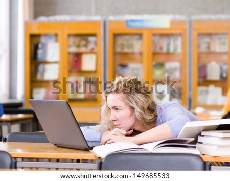 sad student with laptop working in library