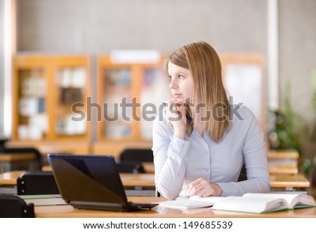 Young student using computer in a library. looking away