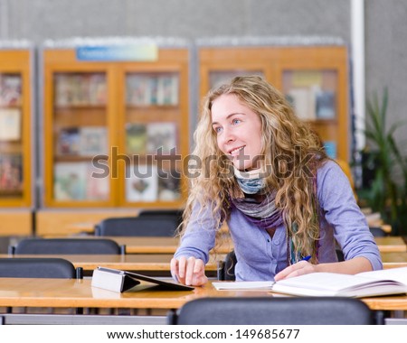 female student with tablet computer in library. looking away