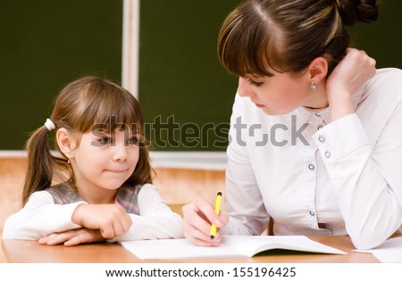 Teacher helps the student with schoolwork in  classroom