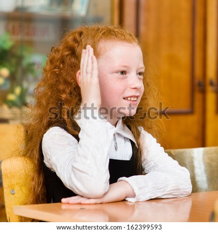 young girl raising hand knowing the answer to the question