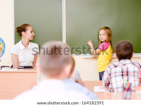 girl answers questions of teachers near a school board