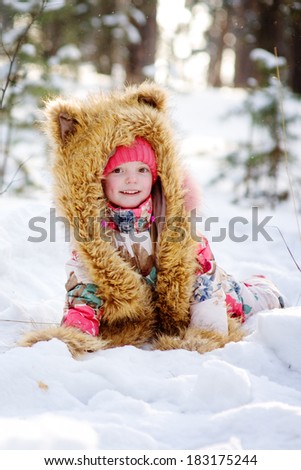 Funny girl in a fur hat in winter forest