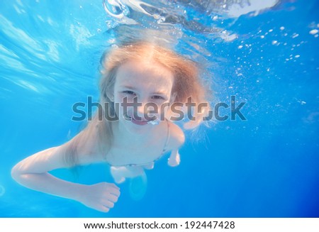 Swimming young girl underwater in pool