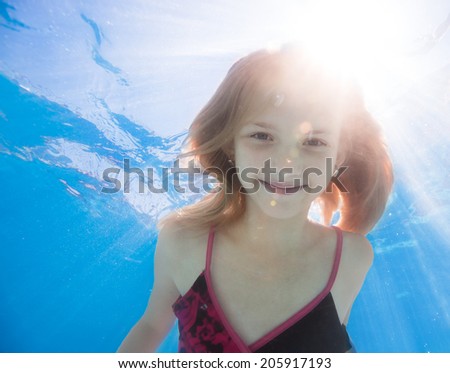 Happy young girl with long haired underwater in pool