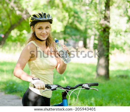 Young woman with mountain bike and bottle of water in hand
